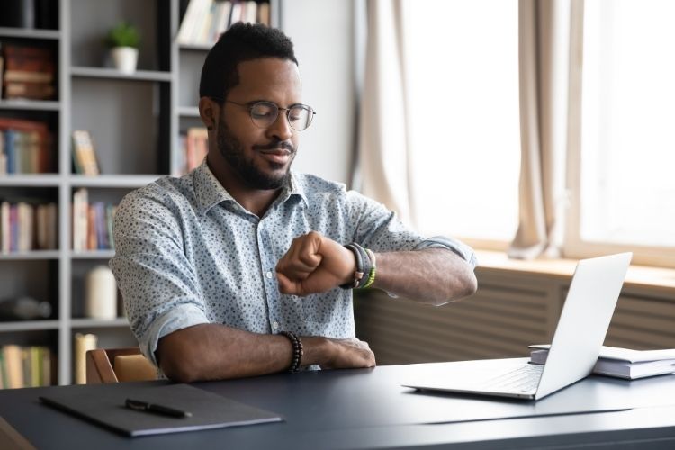 image article blog lms personne qui regarde sa montre devant son ordinateur