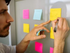 Image Article Homme Qui Ecrit Sur Un Post It Colle Sur Un Tableau