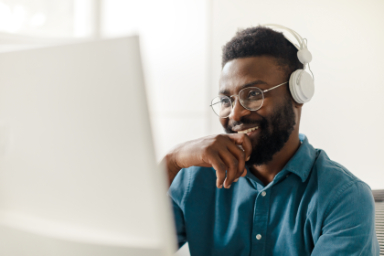 Happy Black Man In Headphones Working On Computer