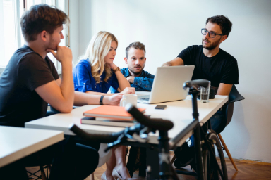 team employees in a meeting with laptops and mics