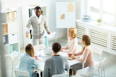 man standing in office during a meeting with team e-learning